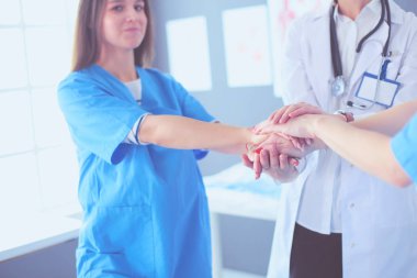 Doktorlar ve hemşireler tıbbi bir ekipte el ele tutuşuyorlar.