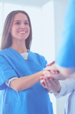 Doktorlar ve hemşireler tıbbi bir ekipte el ele tutuşuyorlar.