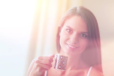 bir bardak süt ile yatakta oturan genç kadın