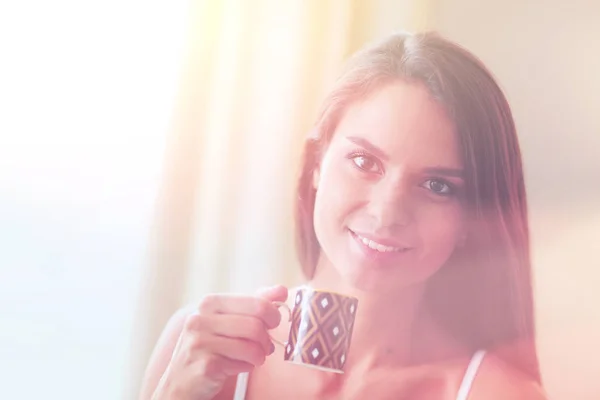 Mujer joven sentada en la cama con una taza de leche — Foto de Stock