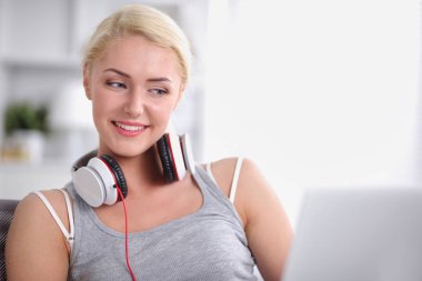 Evdeki genç ve güzel kadın kanepede oturup müzik dinliyor.