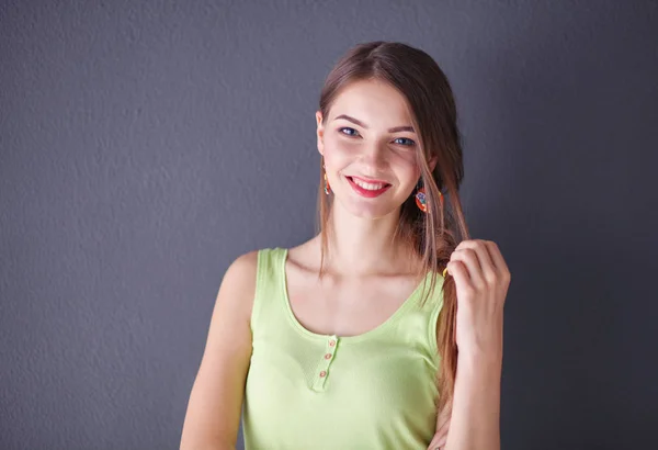 Portret van een jonge glimlachende vrouw op een grijze achtergrond — Stockfoto