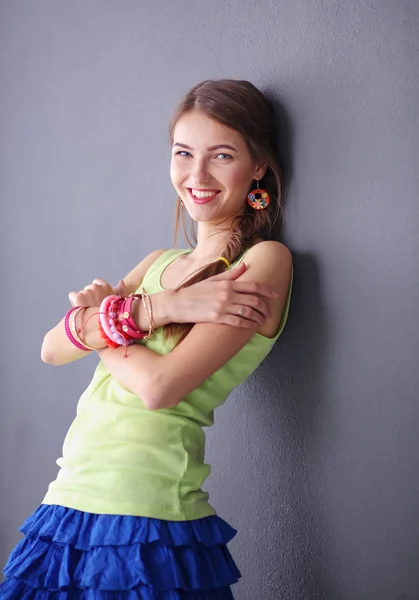 회색 벽을 배경으로 웃고 있는 젊은 여자의 모습 — 스톡 사진