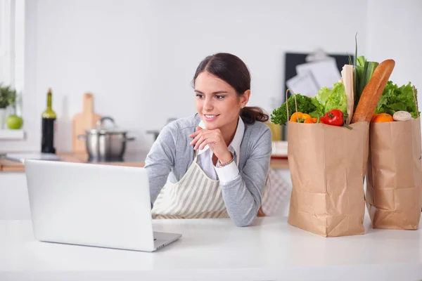 Smiling woman online shopping using computer and credit card in kitchen — Stock Photo, Image