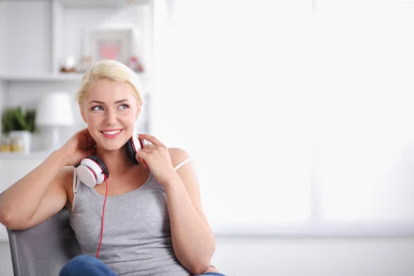 Evdeki genç ve güzel kadın kanepede oturup müzik dinliyor. — Stok fotoğraf