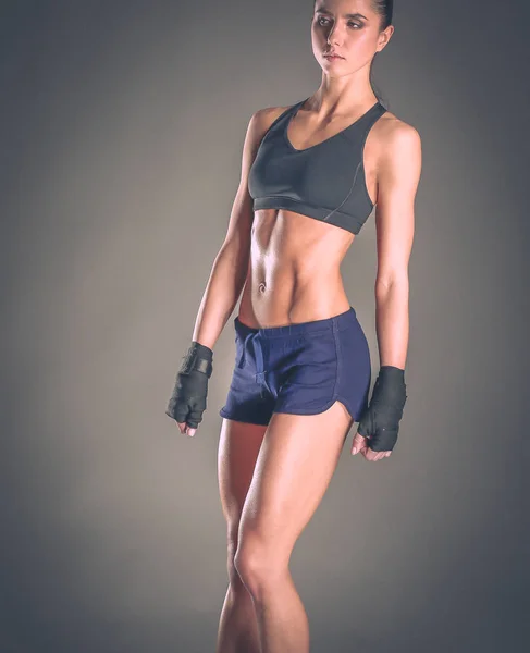 Muscular young woman posing in sportswear against black background — Stock Photo, Image