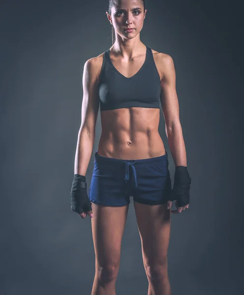 Muscular young woman posing in sportswear against black background — Stock Photo, Image