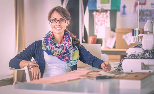 Молода жінка шиє, сидячи на робочому місці — стокове фото