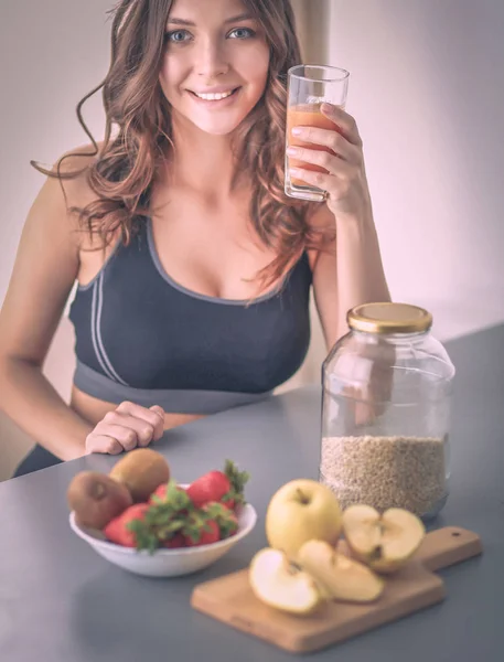 Girl sitting in the kitchen on the desk with fruit and glasses with juice — Stock Photo, Image