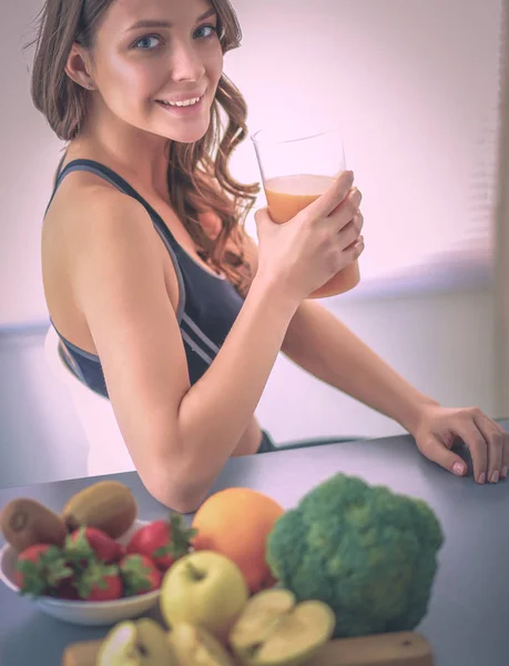 Chica sentada en la cocina en el escritorio con frutas y vasos con jugo — Foto de Stock