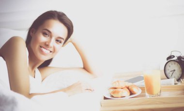 Genç ve güzel bir kadın yatakta yatıyor.