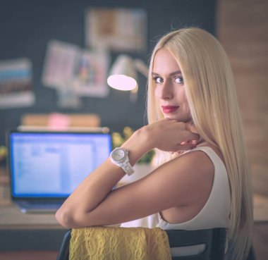 Moda tasarımcıları stüdyoda çalışıyor. Masanın üzerinde oturuyorlar.