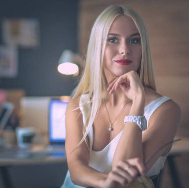 Moda tasarımcıları stüdyoda çalışıyor. Masanın üzerinde oturuyorlar.