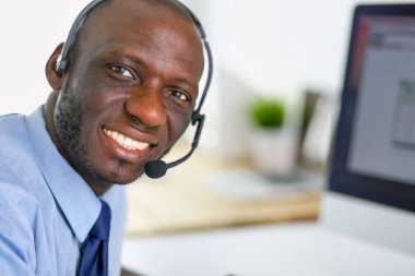 Kulaklıklı Afro-Amerikan işadamı laptopuyla çalışıyor.