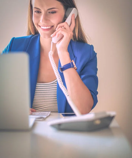 Portret van een jonge vrouw op telefoon achter een laptopcomputer. — Stockfoto