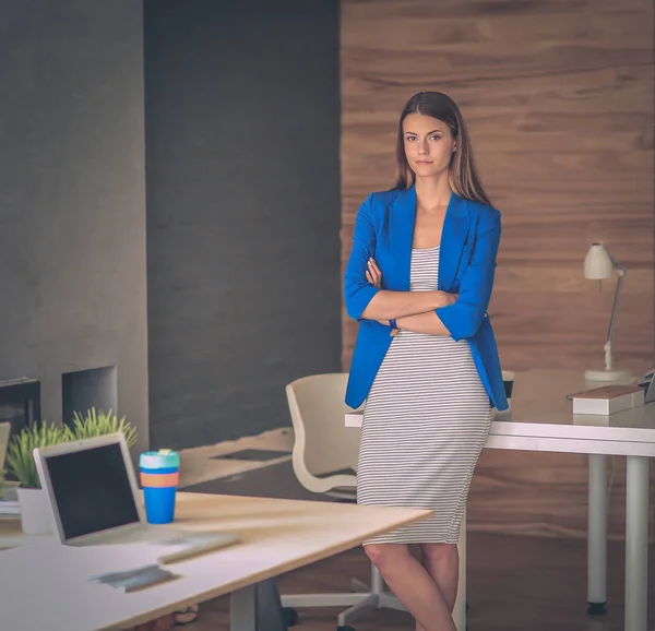 Retrato de uma bela mulher de negócios em pé perto de seu local de trabalho. — Fotografia de Stock