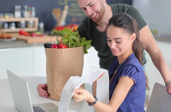Koppel het betalen van hun rekeningen met laptop in de keuken thuis — Stockfoto