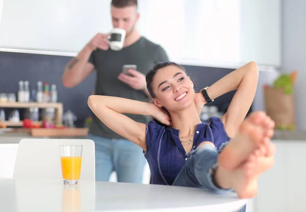 Pareja feliz usando smartphone sentado en la cocina —  Fotos de Stock