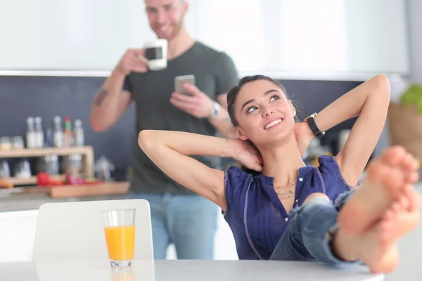 Pareja feliz usando smartphone sentado en la cocina —  Fotos de Stock