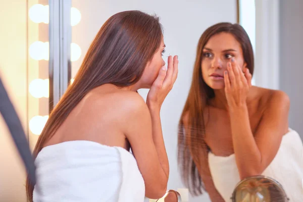 Atractiva joven que aplica crema en su cara — Foto de Stock