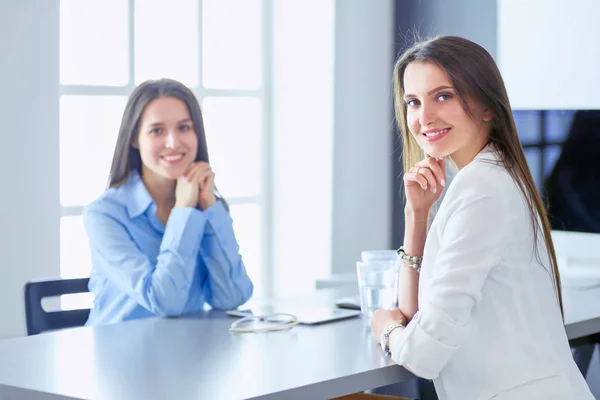 Two female colleagues in office sitting on the desk — Stock Photo, Image