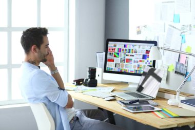 İnternette çalışırken bilgisayarın ve dizüstü bilgisayarın önünde grafik stüdyosunda oturan genç tasarımcının portresi.