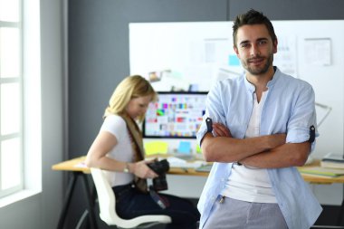 Dizüstü bilgisayar ve bilgisayar çalışırken önünde genç tasarımcı portresi. Onun mobil arka plan kullanarak Yardımcısı.