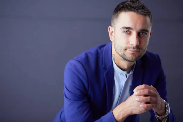 Joven empresario sentado aislado sobre fondo gris. —  Fotos de Stock