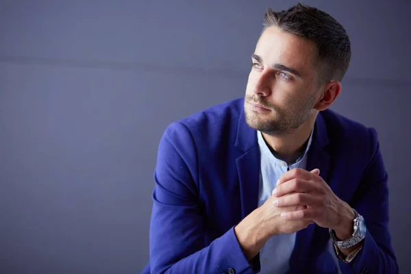 Joven empresario sentado aislado sobre fondo gris. —  Fotos de Stock