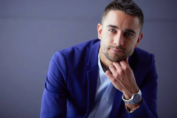 Joven empresario sentado aislado sobre fondo gris. —  Fotos de Stock