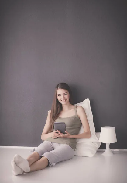 Mujer morena bonita sentada en el suelo con una almohada y mesa de avión — Foto de Stock