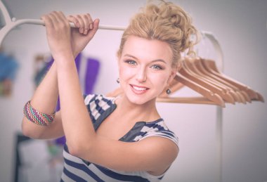 Raf ofiste askıları ile yakınındaki güzel genç stilist