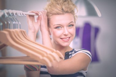 Raf ofiste askıları ile yakınındaki güzel genç stilist