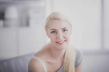 Genç ve güzel bir kadın odasında kanepede oturuyor.