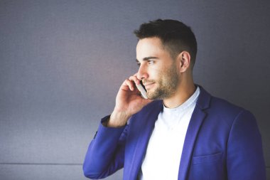 Gri arka planda yalnız oturan genç iş adamı.