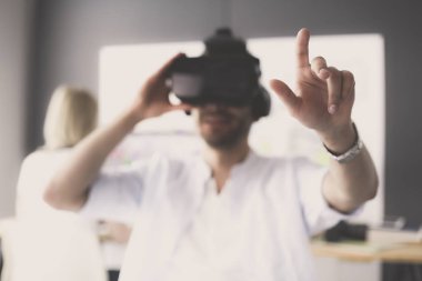 Genç erkek yazılım programcısı ofiste üç boyutlu sanal gerçeklik gözlükleriyle yeni bir uygulama test ediyor..