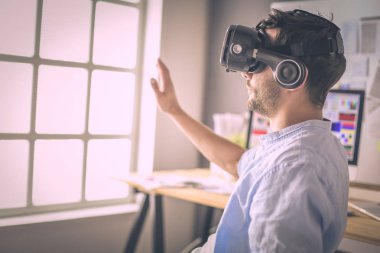 Genç erkek yazılım programcısı ofiste üç boyutlu sanal gerçeklik gözlükleriyle yeni bir uygulama test ediyor..