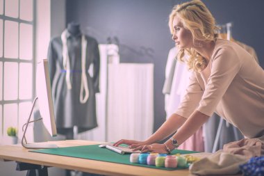 Moda tasarımcısı kadın stüdyoda tasarımları üzerinde çalışıyor..