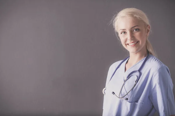 Portret van lachende doctor in de uniforme staande op een grijze achtergrond — Stockfoto