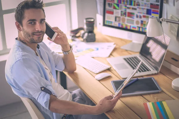 Porträt eines jungen Designers, der im Grafikstudio vor Laptop und Computer sitzt, während er online arbeitet. — Stockfoto