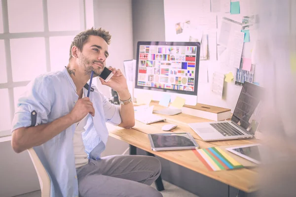 Porträt eines jungen Designers, der im Grafikstudio vor Laptop und Computer sitzt, während er online arbeitet. — Stockfoto