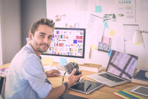 Portret van jonge ontwerper zittend in grafische studio achter laptop en computer terwijl hij online werkt. — Stockfoto
