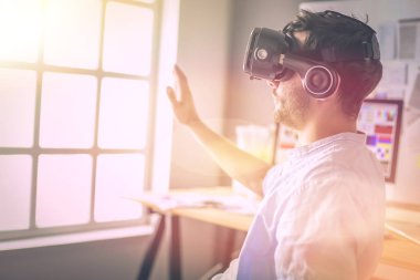 Genç erkek yazılım programcısı ofiste üç boyutlu sanal gerçeklik gözlükleriyle yeni bir uygulama test ediyor..