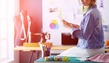 Moda tasarımcısı kadın stüdyoda tasarımları üzerinde çalışıyor.