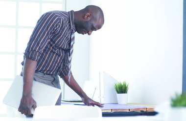 Ofiste bilgisayar ve planlarla çalışan Afrikalı Amerikalı bir mimar.