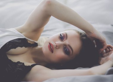 Yatakta seksi, şık bir kadın portresi.