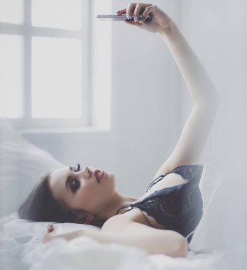 - Günaydın. Yatakta cep telefonu olan tatlı bir kadın.