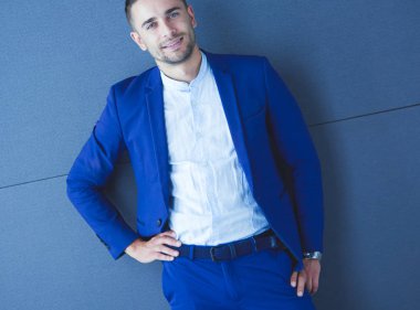 Gri arka planda tek başına duran genç iş adamı