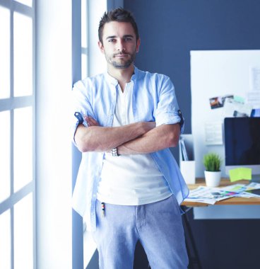 Dizüstü bilgisayar ve bilgisayar çalışırken önünde genç tasarımcı portresi. Onun mobil arka plan kullanarak Yardımcısı.