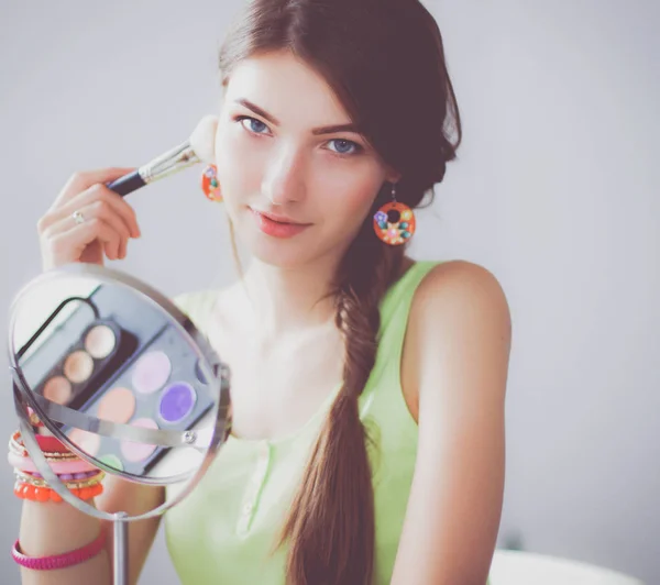 Młoda kobieta piękne Dokonywanie makijaż w pobliżu lustro, siedząc przy biurku — Zdjęcie stockowe